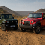 ऑफ-रोड ट्रैक पर चलती हुई दो एसयूवी — एक Maruti Suzuki Jimny और दूसरी Mahindra Thar, दोनों पहाड़ी रास्तों पर धूल उड़ाते हुए दमदार प्रदर्शन दिखा रही हैं, जो “Jimny vs Thar” ऑफ-रोड तुलना को दर्शाती है।